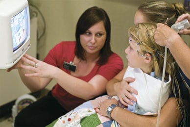 Technician, patient and family watching EEG video monitor